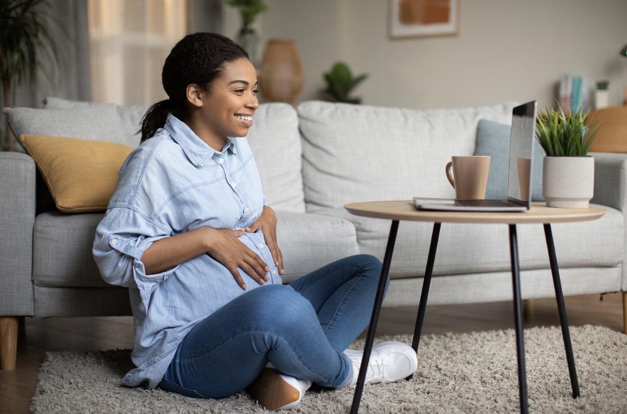 Pregnant woman attending an online session at home with her laptop