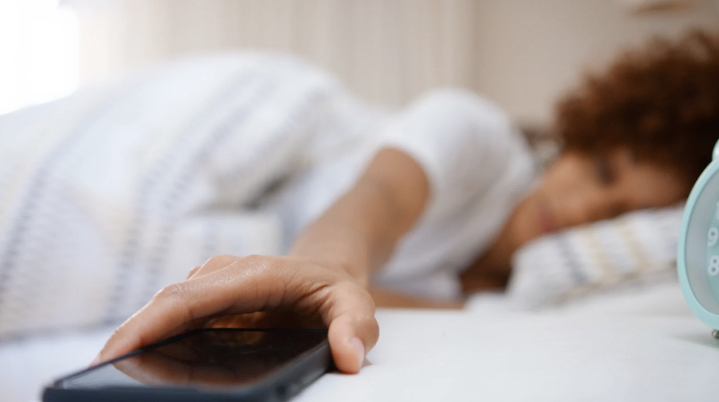Hand reaching for phone on bedside, soft natural light