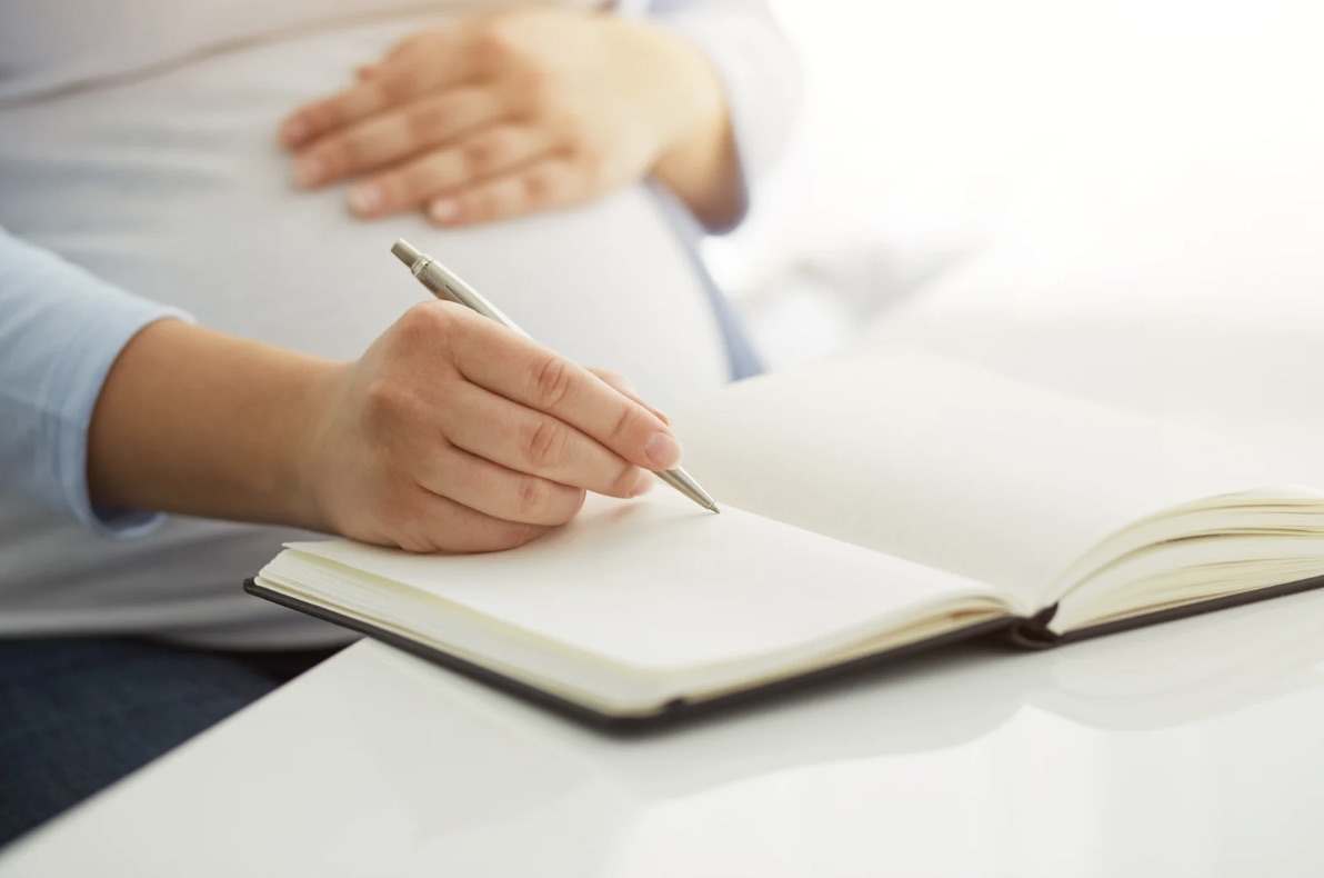 Pregnant woman writing in journal, planning her birth preferences