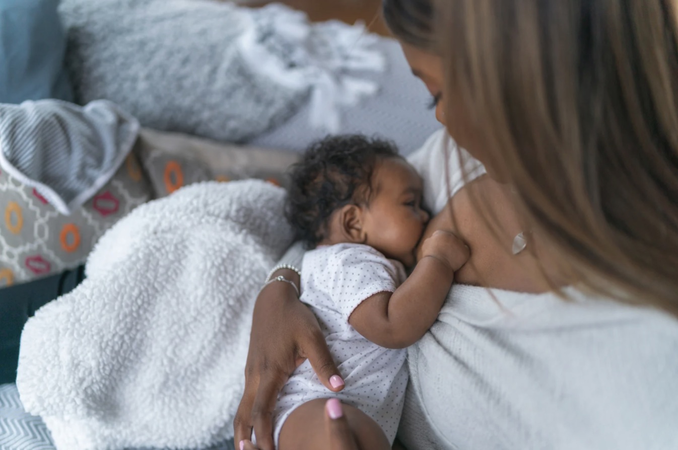 Mother breastfeeding her baby in soft natural light, top-down view