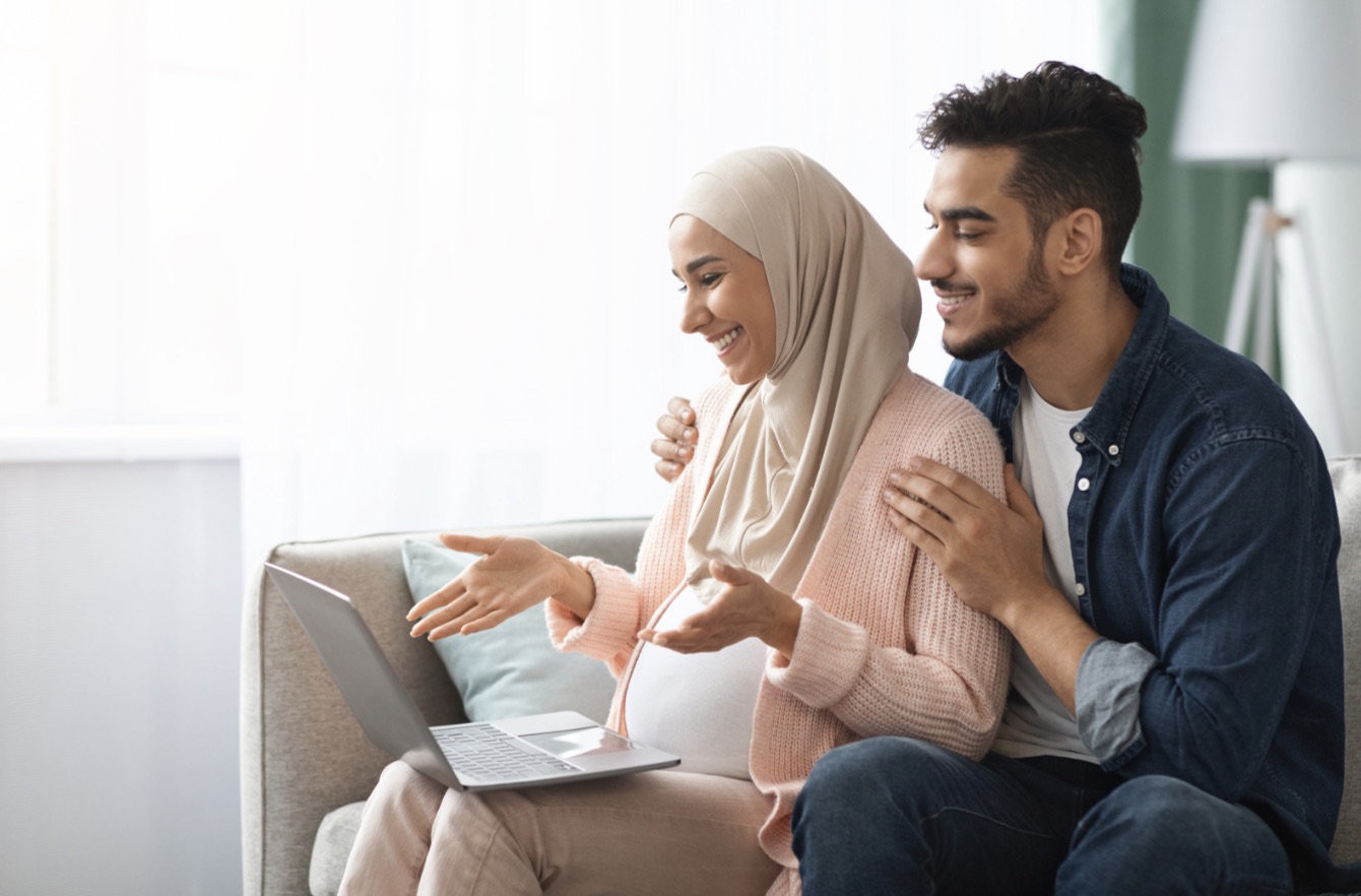 Pregnant couple on a video call together at home, engaged conversation